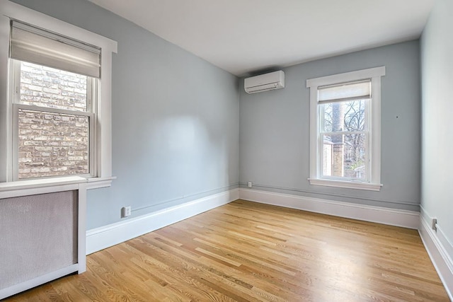 spare room featuring light hardwood / wood-style flooring and a wall unit AC