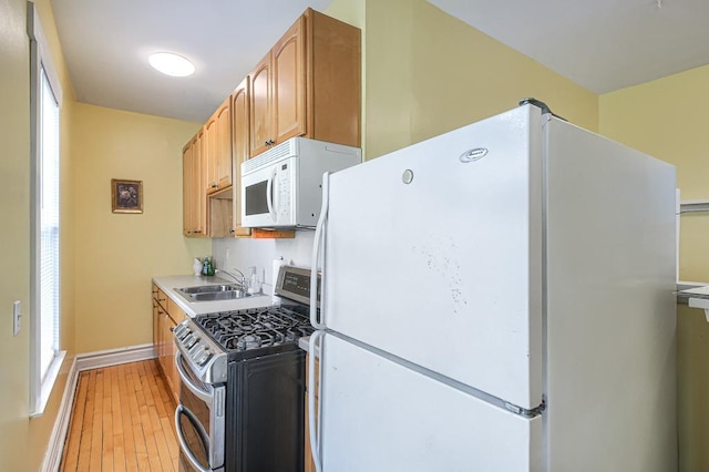 kitchen featuring white appliances, wood-type flooring, and sink