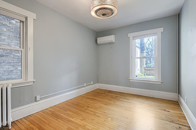 unfurnished room featuring light wood-type flooring, plenty of natural light, radiator heating unit, and an AC wall unit