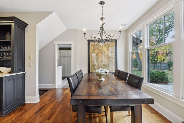 dining area with dark hardwood / wood-style flooring and an inviting chandelier