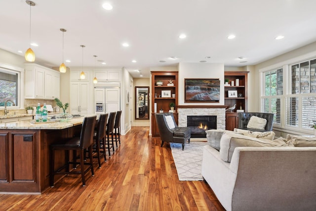 living room featuring hardwood / wood-style floors, a stone fireplace, and sink