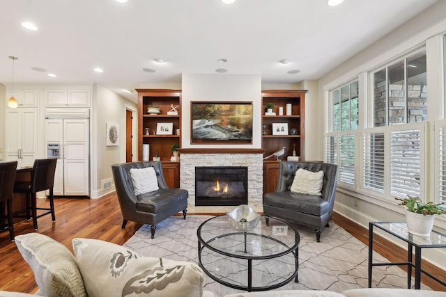 living room with a fireplace, light wood-type flooring, and built in features