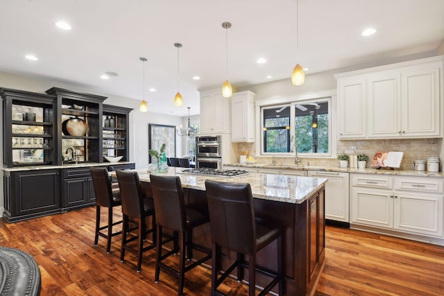 kitchen with double oven, white cabinets, a center island, and hanging light fixtures