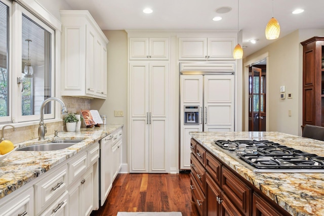 kitchen featuring stainless steel gas cooktop, light stone countertops, dark hardwood / wood-style floors, sink, and decorative light fixtures