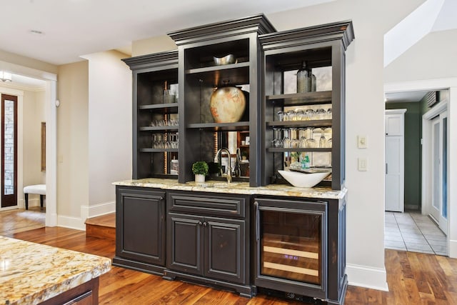 bar with sink, beverage cooler, light stone counters, and dark hardwood / wood-style floors