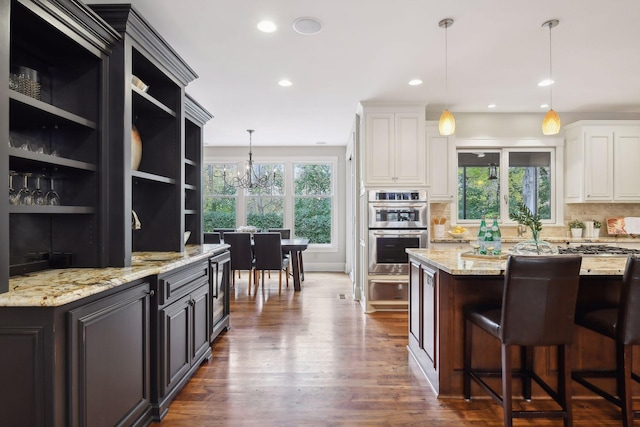 kitchen featuring backsplash, white cabinets, stainless steel double oven, and pendant lighting