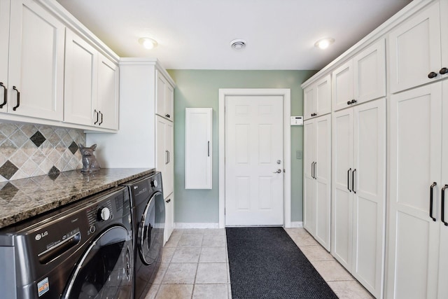 washroom featuring washing machine and dryer, cabinets, and light tile patterned floors