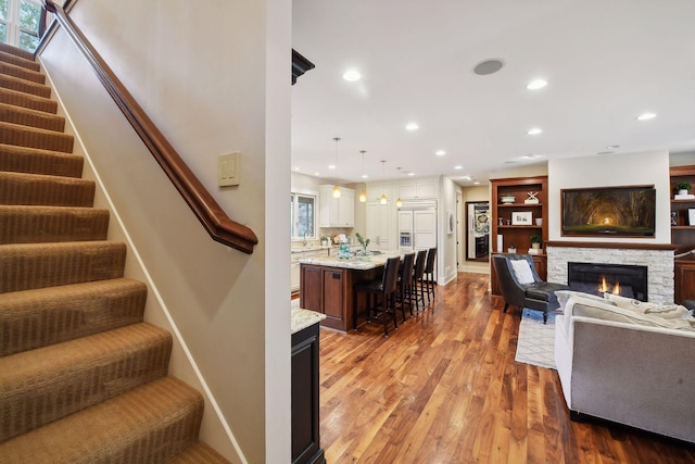 living room featuring sink, a fireplace, hardwood / wood-style floors, and a healthy amount of sunlight