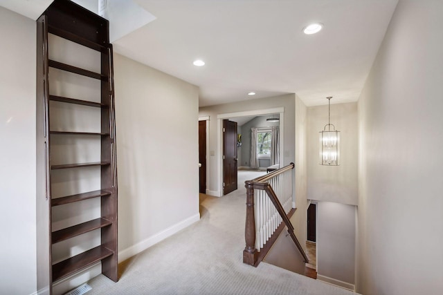 hallway featuring light colored carpet and an inviting chandelier