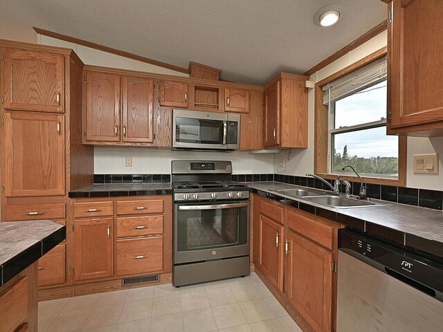 27602 County Road 51, Bovey, MN 55709 - kitchen with dark countertops, brown cabinets, a sink, and appliances with stainless steel finishes