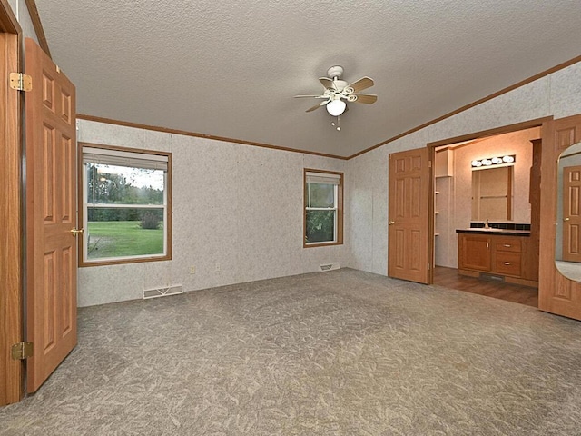 27602 County Road 51, Bovey, MN 55709 - unfurnished bedroom featuring visible vents, ornamental molding, vaulted ceiling, wallpapered walls, and carpet flooring