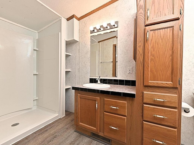 27602 County Road 51, Bovey, MN 55709 - bathroom with crown molding, a shower stall, vanity, visible vents, and wood finished floors