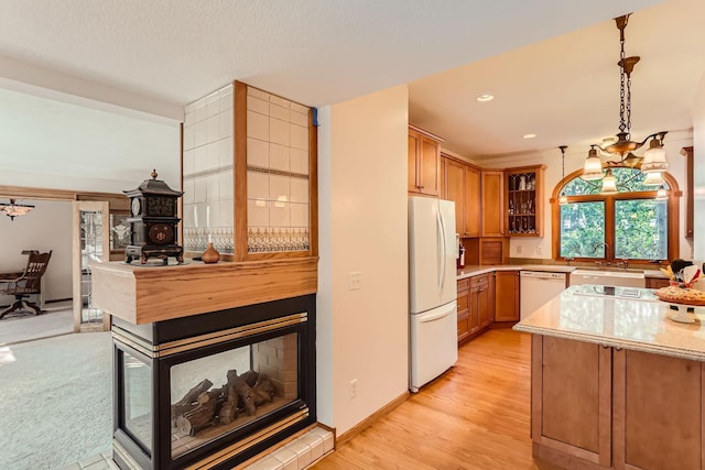 kitchen featuring sink, light hardwood / wood-style flooring, a chandelier, pendant lighting, and white appliances