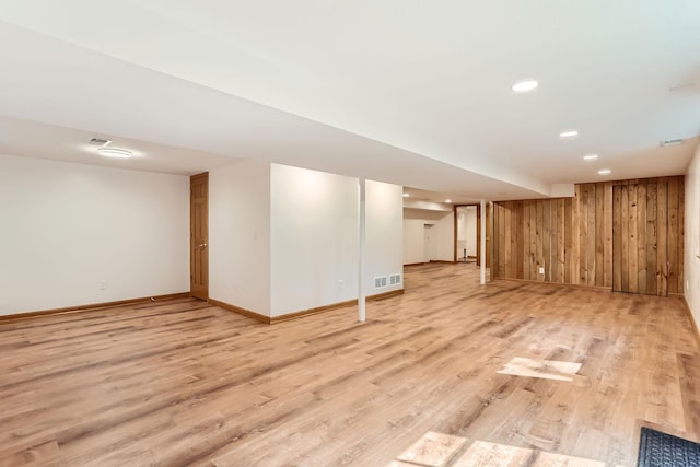 basement with light wood-type flooring and wood walls