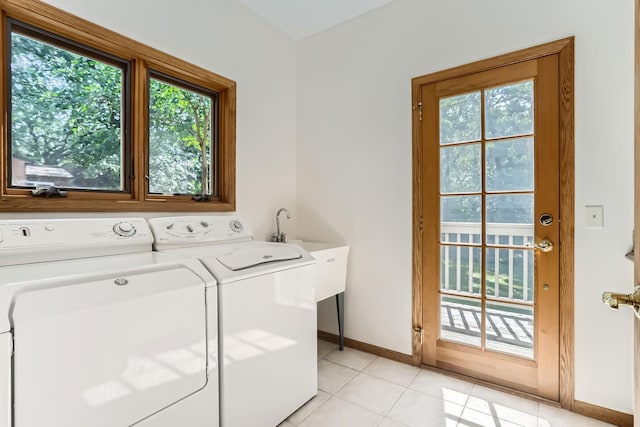 laundry area with light tile patterned floors, washer and clothes dryer, and sink