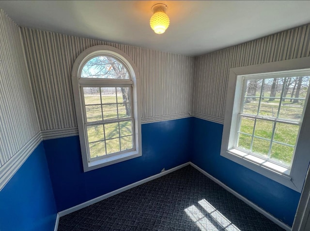 empty room featuring baseboards and dark carpet