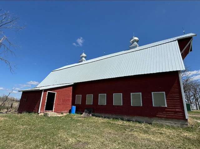 view of property exterior featuring a yard, metal roof, and an outbuilding