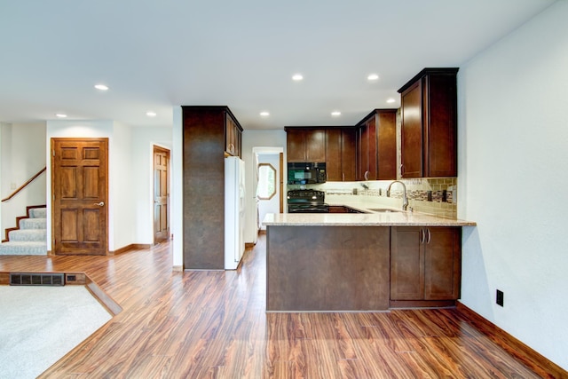 kitchen featuring black appliances, kitchen peninsula, sink, and dark hardwood / wood-style flooring