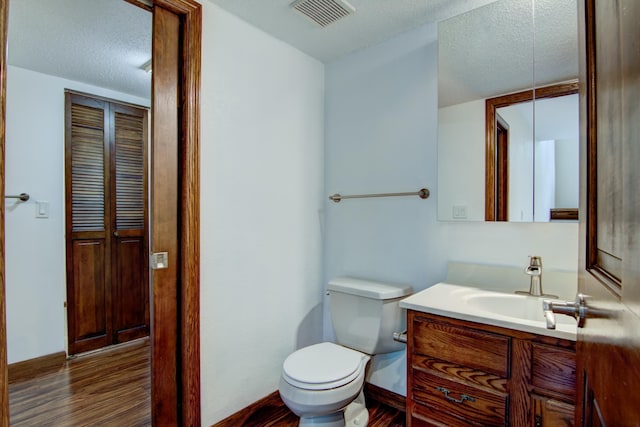 bathroom with a textured ceiling, hardwood / wood-style floors, vanity, and toilet