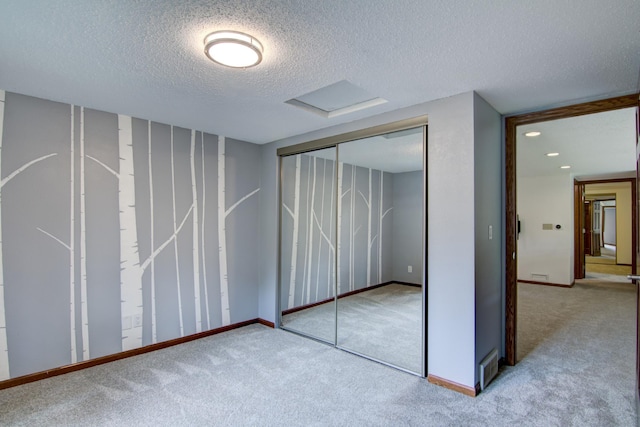 unfurnished bedroom featuring a textured ceiling, a closet, and carpet flooring