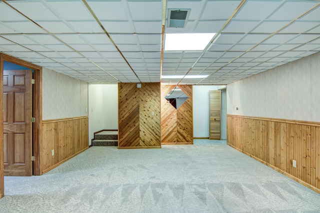 basement featuring light carpet and wood walls