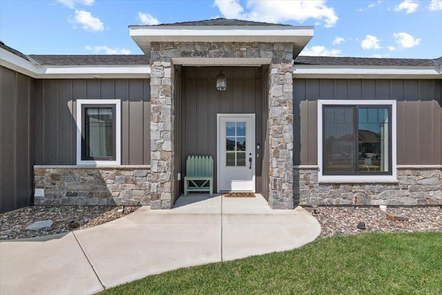 property entrance with board and batten siding, stone siding, and a shingled roof