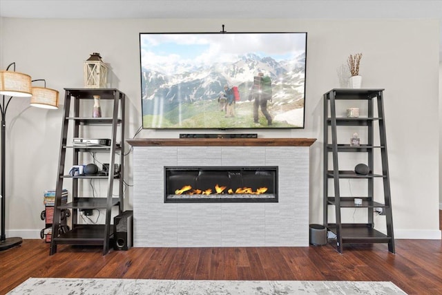 living room featuring a fireplace, baseboards, and wood finished floors