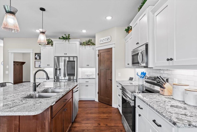 kitchen featuring a kitchen island with sink, a sink, stainless steel appliances, white cabinets, and dark wood-style flooring