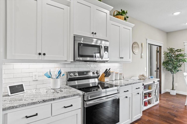 kitchen with baseboards, dark wood finished floors, decorative backsplash, white cabinets, and appliances with stainless steel finishes