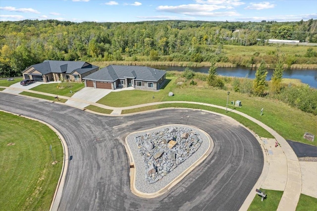 drone / aerial view with a wooded view and a water view