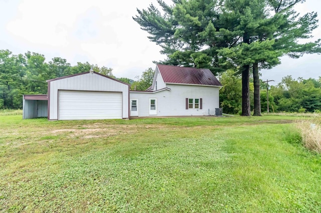 rear view of property with cooling unit, a lawn, and a garage