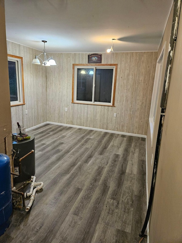 empty room featuring a notable chandelier, hardwood / wood-style floors, and wooden walls