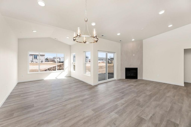 unfurnished living room with light wood-style floors, lofted ceiling, a large fireplace, and a healthy amount of sunlight