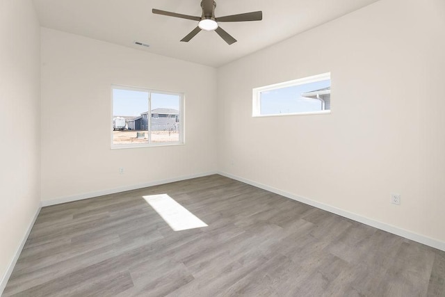 empty room with hardwood / wood-style flooring, ceiling fan, and a healthy amount of sunlight