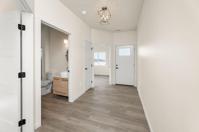 hall with light hardwood / wood-style flooring and a notable chandelier