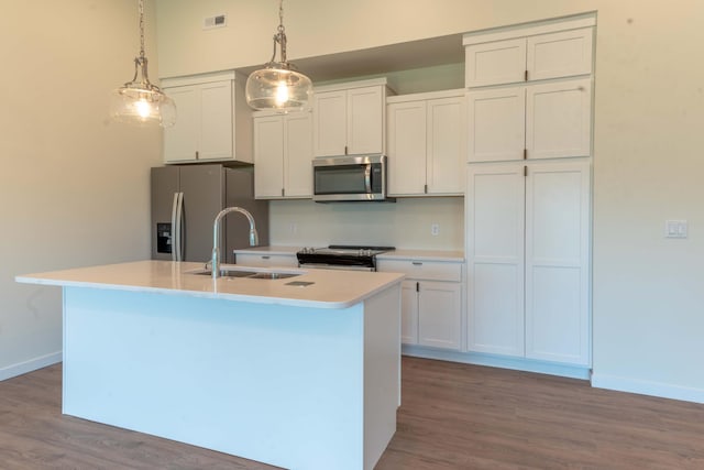 kitchen featuring decorative light fixtures, appliances with stainless steel finishes, an island with sink, sink, and white cabinetry