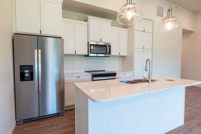 kitchen featuring white cabinets, hanging light fixtures, appliances with stainless steel finishes, sink, and an island with sink