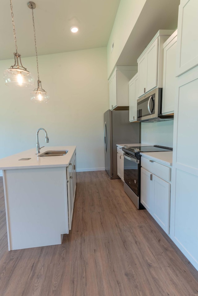 kitchen with pendant lighting, wood-type flooring, sink, appliances with stainless steel finishes, and white cabinets