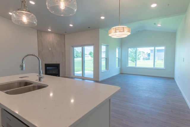 kitchen with hanging light fixtures, a large fireplace, sink, hardwood / wood-style flooring, and lofted ceiling