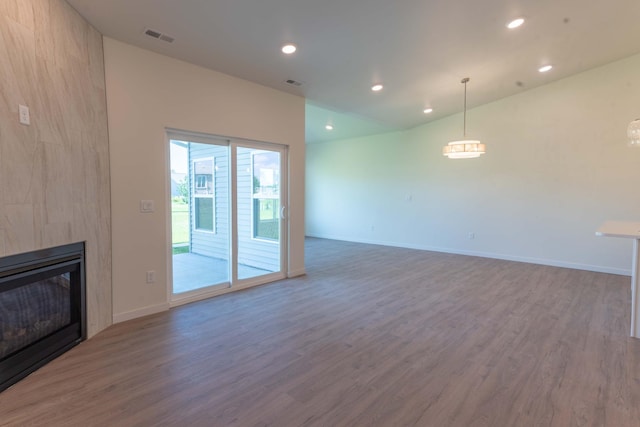 unfurnished living room with dark wood-type flooring, vaulted ceiling, and a fireplace