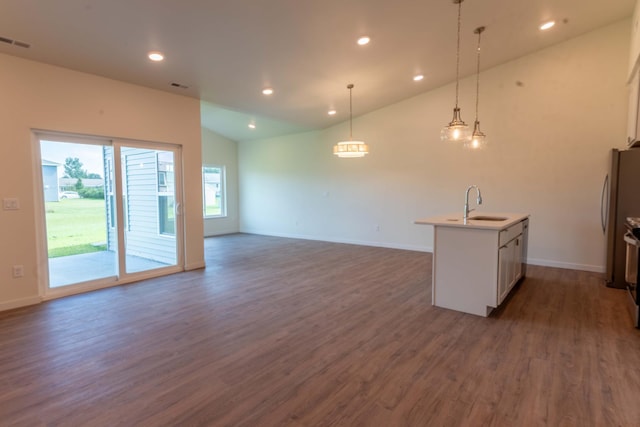 kitchen featuring stainless steel fridge, decorative light fixtures, dark hardwood / wood-style flooring, an island with sink, and sink