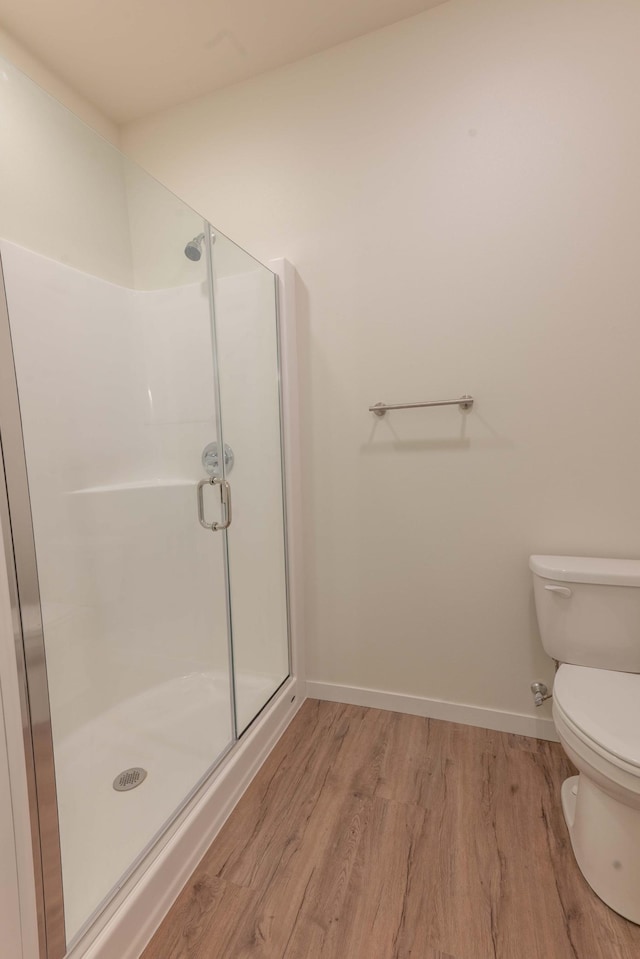 bathroom with a shower with door, toilet, and hardwood / wood-style floors