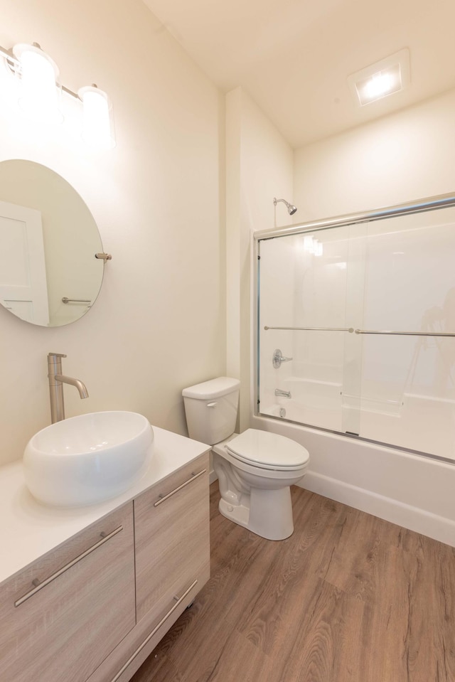 full bathroom with shower / bath combination with glass door, vanity, toilet, and hardwood / wood-style flooring