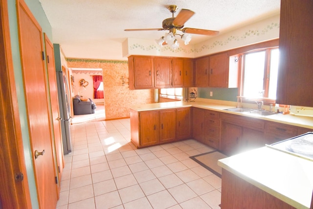 102 6th St SW, Red Lake Falls, MN 56750 - kitchen with wallpapered walls, a sink, brown cabinetry, ceiling fan, and light countertops