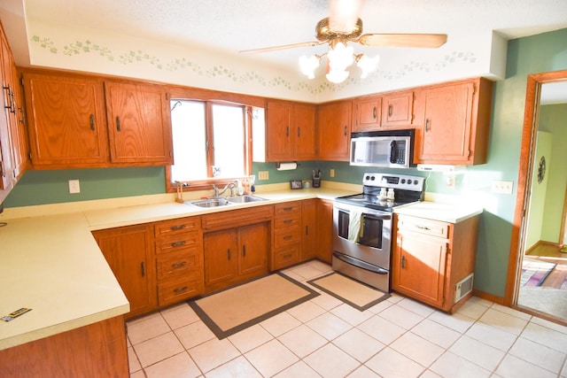 102 6th St SW, Red Lake Falls, MN 56750 - kitchen with stainless steel appliances, a sink, a ceiling fan, brown cabinets, and light countertops