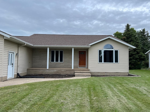 ranch-style home featuring a front yard, covered porch, and roof with shingles