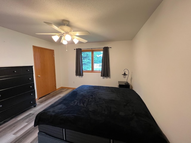 bedroom featuring light wood-style floors, ceiling fan, and a textured ceiling