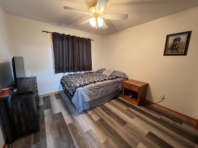 bedroom with ceiling fan, a textured ceiling, baseboards, and wood finished floors