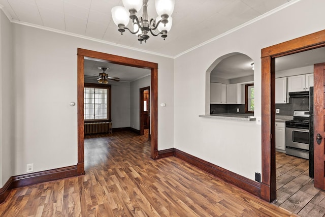 unfurnished dining area with radiator, crown molding, dark wood-type flooring, and ceiling fan with notable chandelier