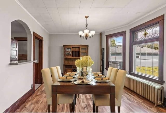 dining space featuring hardwood / wood-style floors, cooling unit, ornamental molding, radiator heating unit, and a chandelier